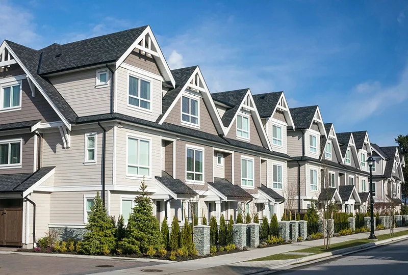 A row of houses with trees in front.
