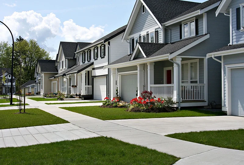 A row of houses with a sidewalk in front.